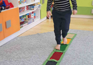 Dzieci boso spacerują po ścieżce sensorycznej
