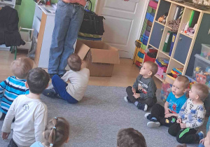 Pani florystka opowiada o swojej pracy, dzieci siedzą na dywanie i uważnie słuchają