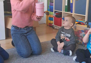 Pani florystka opowiada o swojej pracy, dzieci siedzą na dywanie i uważnie słuchają