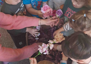 Dzieci oglądają sztuczne kwiaty przyniesione przez florystkę