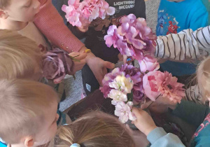 Dzieci oglądają sztuczne kwiaty przyniesione przez florystkę