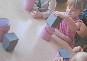 Przedszkolaki wkładają gąbkę do pudełek