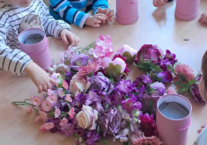 Na stoliku rozłożone sztuczne kwiaty