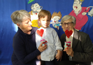 Chłopiec w błękitnej koszuli stoi między dwiema babciami