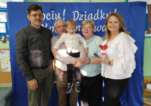 Babcie i dziadkowie trzymają chłopca na rękach