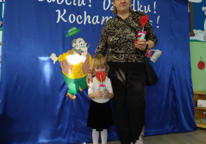 Dziewczynka w czarnej spódniczce stoi obok babci