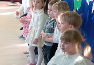 Dzieci stoją na tle dekoracji i śpiewają piosenkę