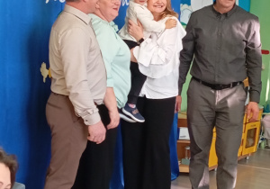 Chłopiec stoi z babciami i dziadkami