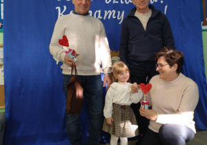 Dziewczynka stoi na tle dekoracji z babciami i dziadkami