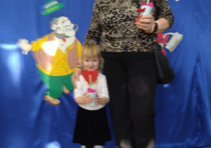 Dziewczynka stoi na tle dekoracji z babcią