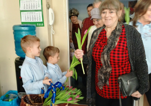 dzieci witają gości symbolicznym kwiatkiem