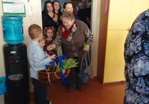 dzieci witają gości symbolicznym kwiatkiem