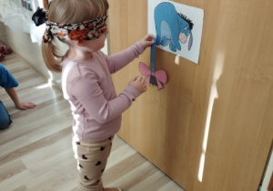 Dziewczynka próbuje doczepić ogon Kłapouchemu