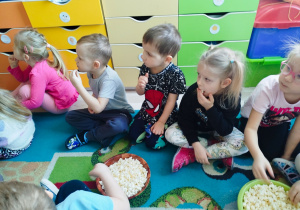 Dzieci oglądają bajkę i jedzą popcorn