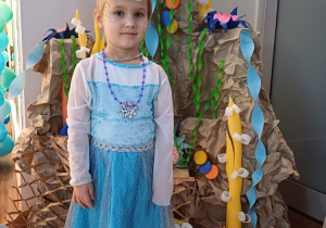 Dziewczynka prezentuje swoją suknię, pozując na tle kolorowej, podwodnej dekoracji