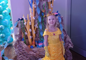 Dziewczynka prezentuje swoją suknię, pozując na tle kolorowej, podwodnej dekoracji