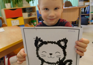 Chłopiec w jasnych włosach trzyma pracę kota.