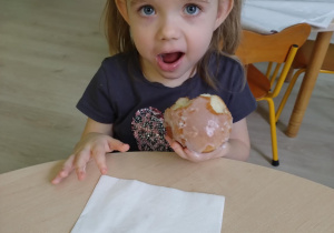 Dziewczynka w koszulce na krótki rękaw je pączka.