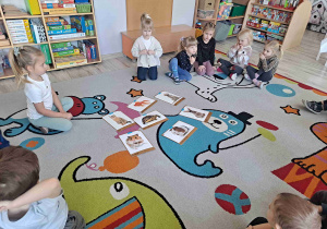 Dzieci siedzą w kole wokół zdjęć zwierząt