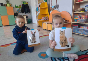Chłioec trzyma grafikę królika, obok dziewczynka trzyma grafikę kota