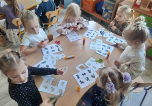 Dzieci siedzą przy stoliku wukonując kartę pracy