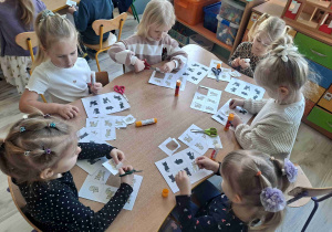 Dzieci siedzą przy stoliku wukonując kartę pracy