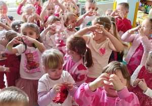 Dzieci wesoło tańczą w sali w rytm muzyki.