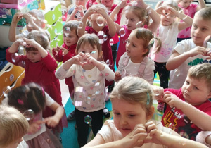 Dzieci wesoło tańczą w sali w rytm muzyki.