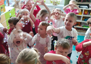 Dzieci wesoło tańczą w sali w rytm muzyki.