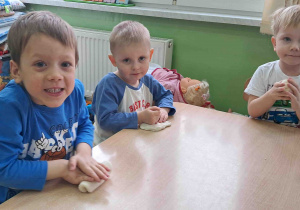 Dzieci przy stoliku wygniatają masę solną