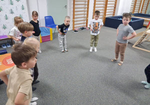 Dzieci stoją w kole i ćwiczą mięsnie stóp.