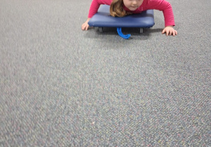 Dziecko ćwiczy na deskorolce terapeutycznej.