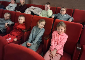 Dzieci siedzą na sali widowiskowej w kinie i czekają na spektakl.
