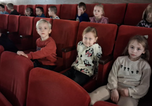 Dzieci siedzą na sali widowiskowej w kinie i czekają na spektakl.