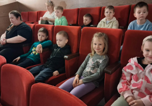 Dzieci siedzą na sali widowiskowej w kinie i czekają na spektakl.