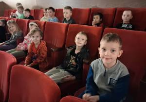 Dzieci siedzą na sali widowiskowej w kinie i czekają na spektakl.