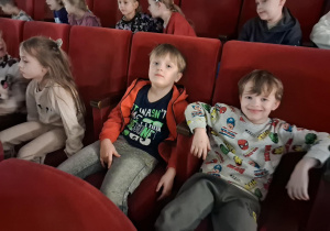 Dzieci siedzą na sali widowiskowej w kinie i czekają na spektakl.