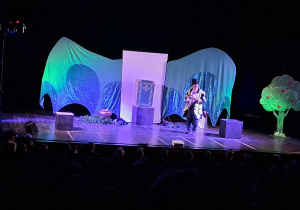 Scena z dekoracją do spektaklu Smocze opowieści. Aktorzy występują.