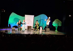 Scena z dekoracją do spektaklu Smocze opowieści. Aktorzy występują.