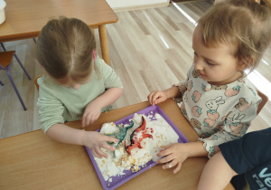 Dziewczynki bawią się cieczą nienewtonowską i figurkami dinozaurów