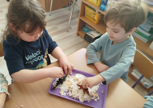 Chłopiec i dziewczynka bawią się figurkami dinozaurów