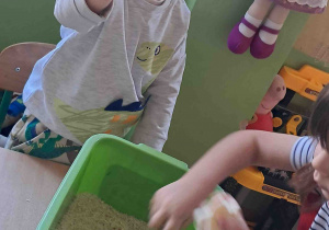 Dzieci wyszukują kości dinozaurów w kaszy, ryżu