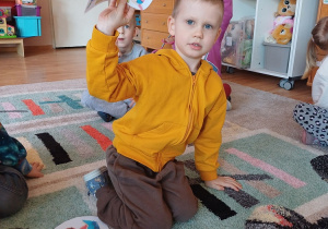 Dzieci uczestniczą w zajęciach dydaktycznych na dywanie, dopasowując obrazki