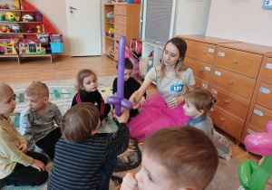 Dzieci z zaciekawieniem obserwują animatora, który tworzy kolorowe zabawki z balonów