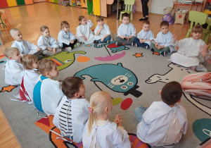 Dzieci siedzą na dywanie podczas warsztatów medycznych