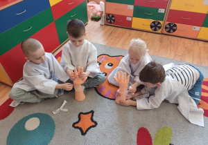 Dzieci ćwiczą bandażowanie ręki na modelach