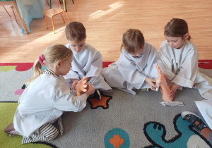 Dzieci ćwiczą bandażowanie ręki na modelach