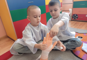 Dzieci uczą się, jak prawidłowo założyć bandaż na rękę podczas zajęć z pierwszej pomocy