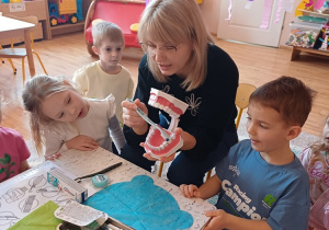 Dzieci z zainteresowaniem obserwują pokaz prawidłowego szczotkowania zębów