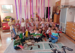 Chłopcy i dziewczynki pozują do pamiątkowego zdjęcia, prezentując swoje upominki